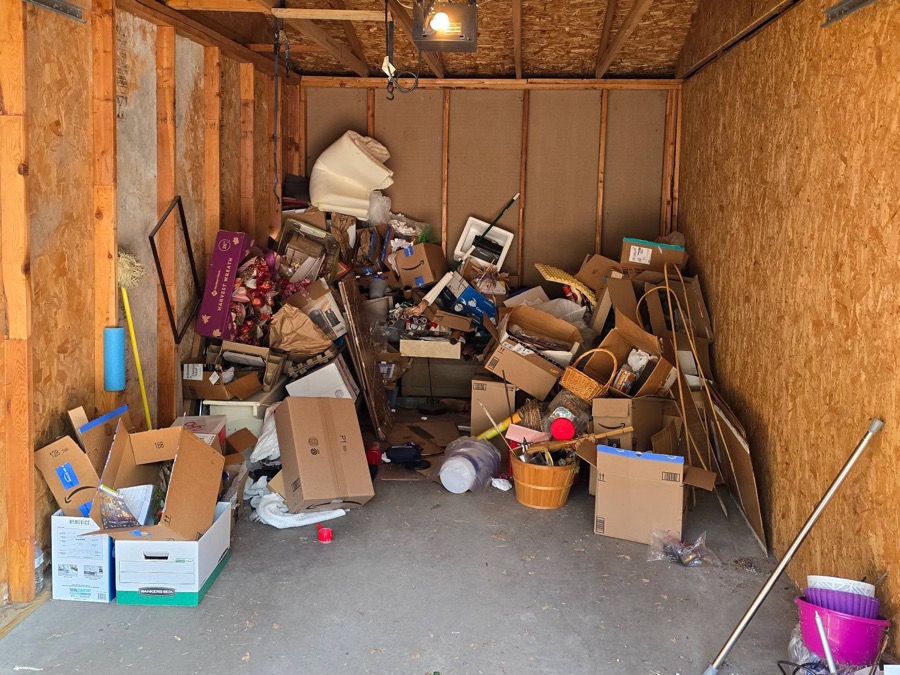 Garage piled with boxes and clutter before a G.O.A.T. cleanout