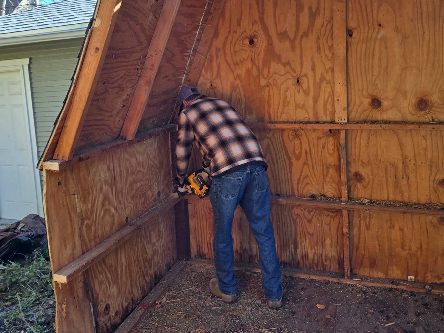 G.O.A.T. Junk Removal crew member tearing down a backyard shed